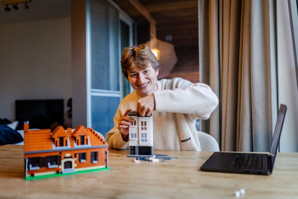 Robin Mortier bouwt aan tafel een huis in bouwsteentjes, vooraan een afgewerkt huis