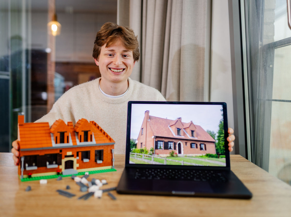 Robin Mortier, oprichter van OurBricks, aan tafel met een huis in bouwsteentjes en de foto van datzelfde huis op zijn laptop
