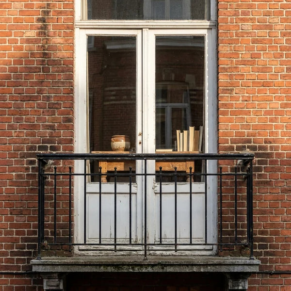 Klein balkon met zwarte balustrade aan een rode bakstenen stadswoning