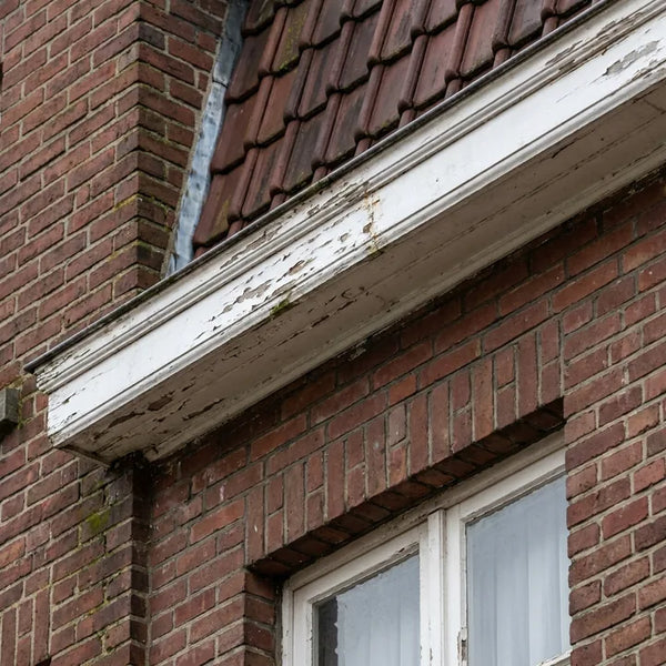 Witte kroonlijst onder de dakrand van een halfopen bakstenen woning