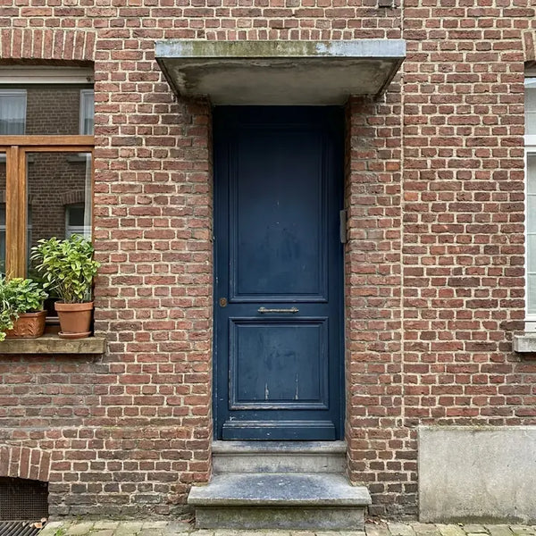 Donkerblauwe voordeur met opstapje en luifel in een bakstenen rijhuis